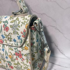 Crossbody, multi-colored floral pattern printed on a cream leather base.